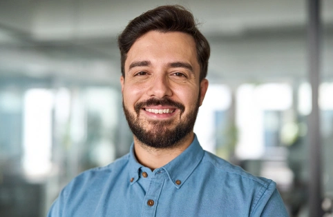 Professional man smiling at camera in modern dental office setting, wearing blue shirt.