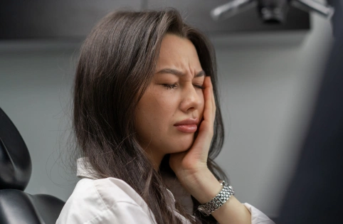 Woman resting her face against her hand in modern dental office setting.