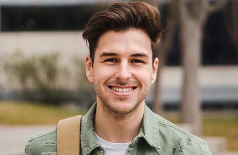 Smiling young man in green shirt outdoors during daytime, professional headshot style portrait.