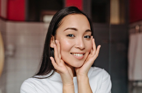 Smiling woman with hands to face in dental office setting, representing patient satisfaction and dental care.
