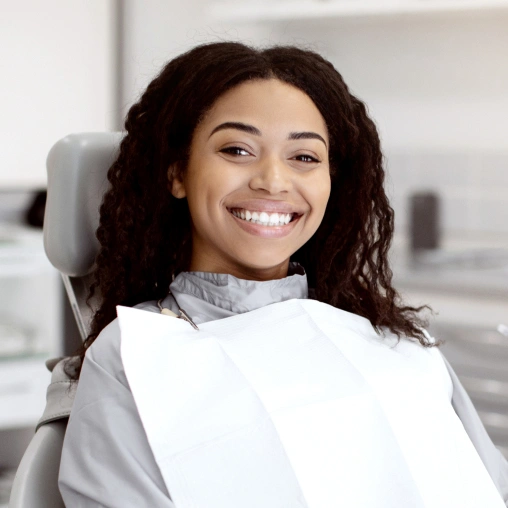 Smiling woman in dental chair wearing bib at modern dental office