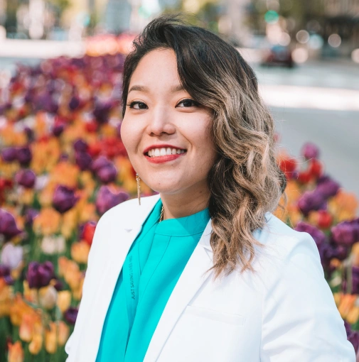 Professional outdoor headshot of Dr. Ariee Jung in a white doctor's coat.