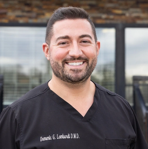 Professional headshot of Dr. Domenic G. Lombardi in black medical scrubs.